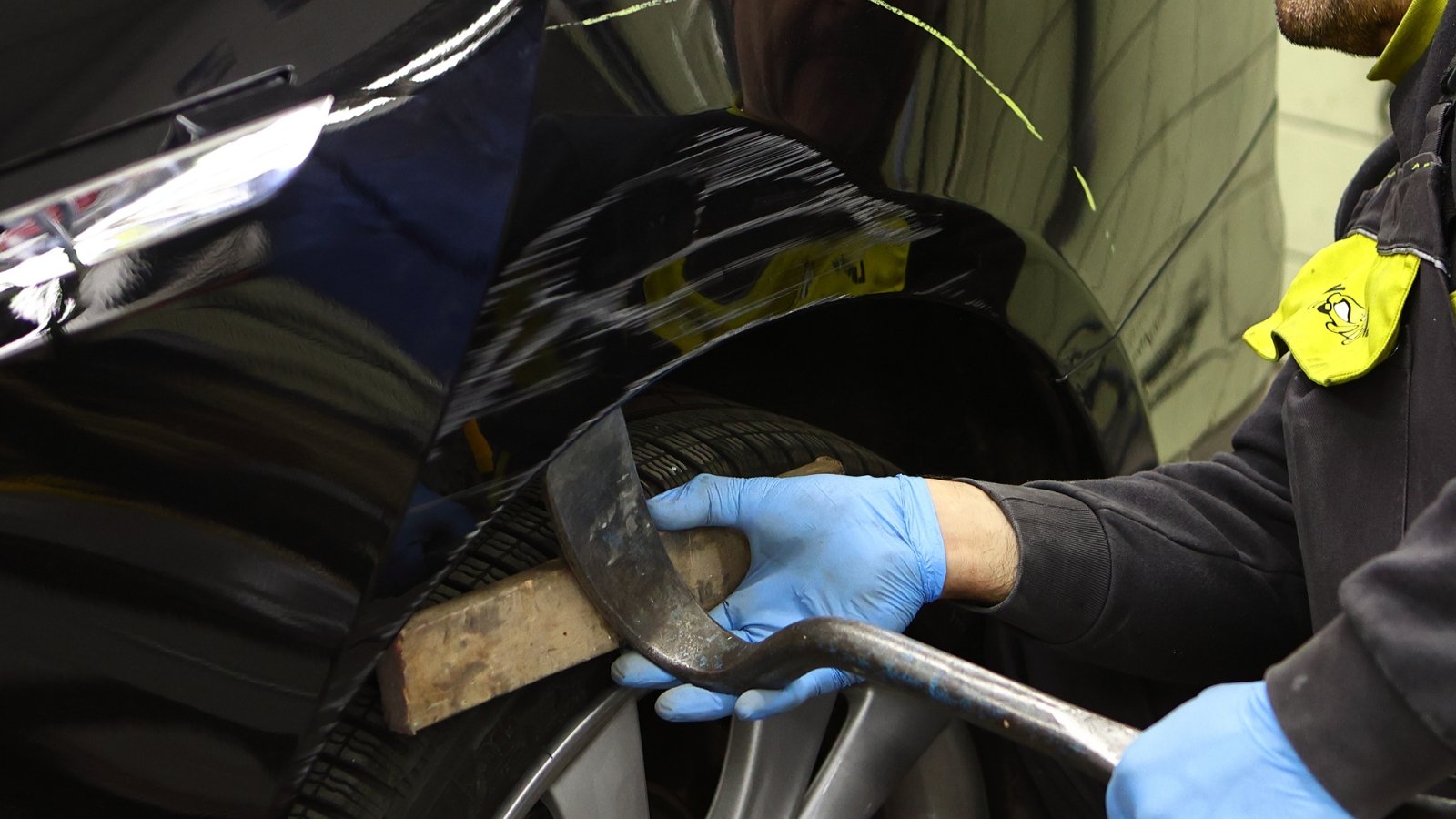 Mechaniker behebt Delle am schwarzen Autokotflügel