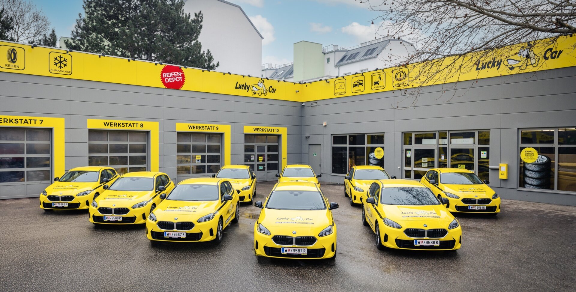 Gelbe Firmenautos vor Lucky Car Werkstatt