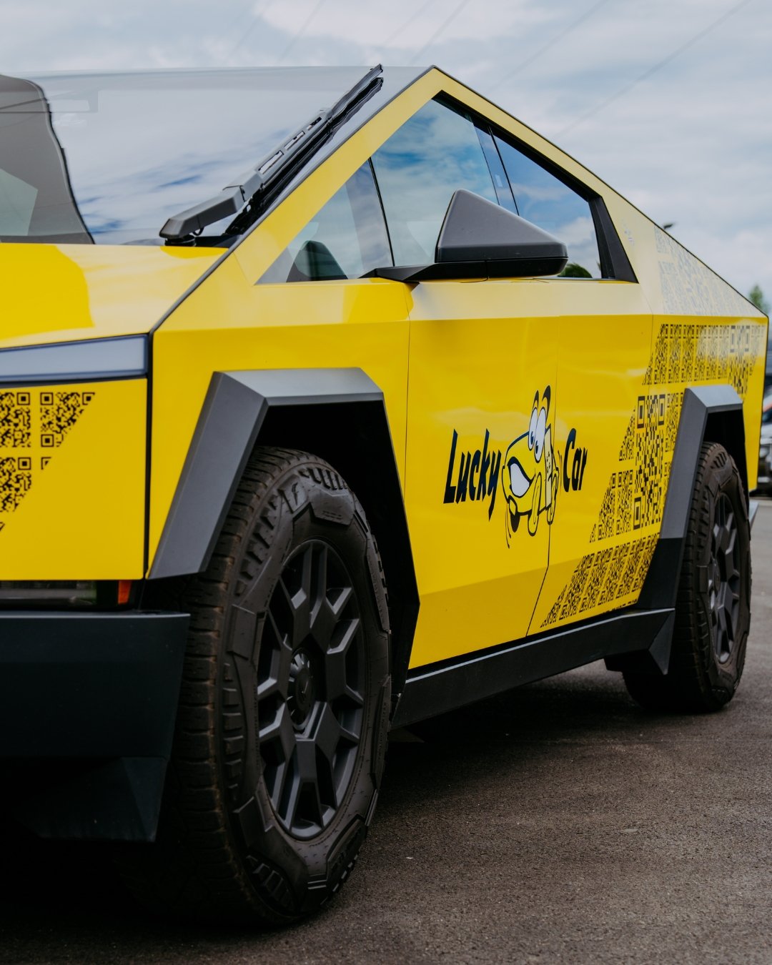 Gelbes, kantiges Elektroauto mit Lucky-Car-Beklebung und QR-Codes