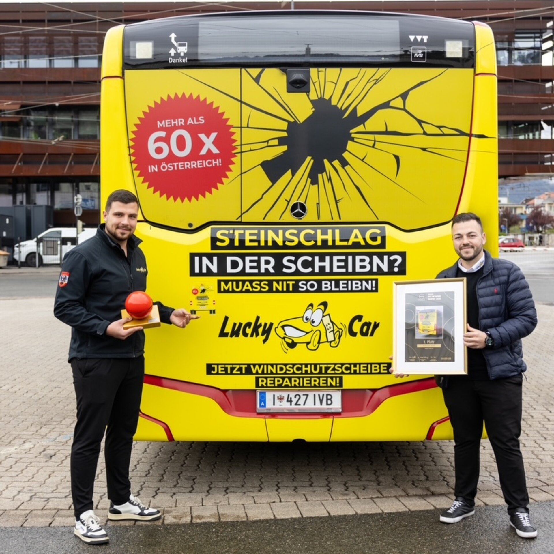 Zwei Männer vor gelbem Bus mit Werbegrafik