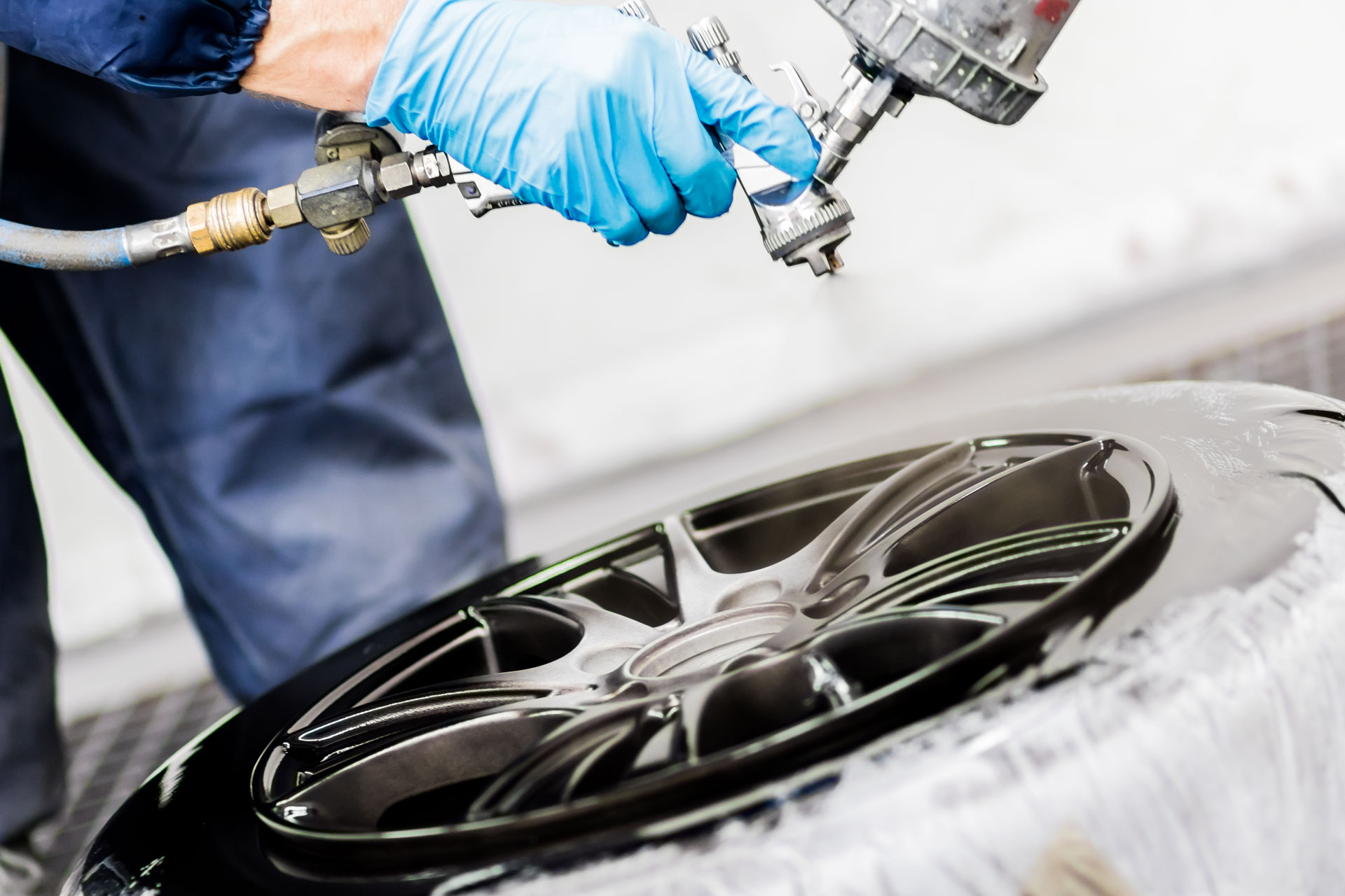 Felge wird mit Lackierpistole professionell lackiert